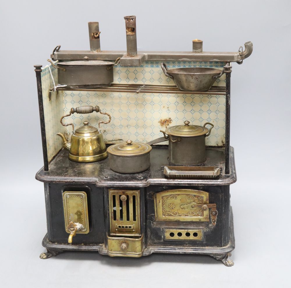 A German tin plate miniature stove, with cooking utensils, height 39cm